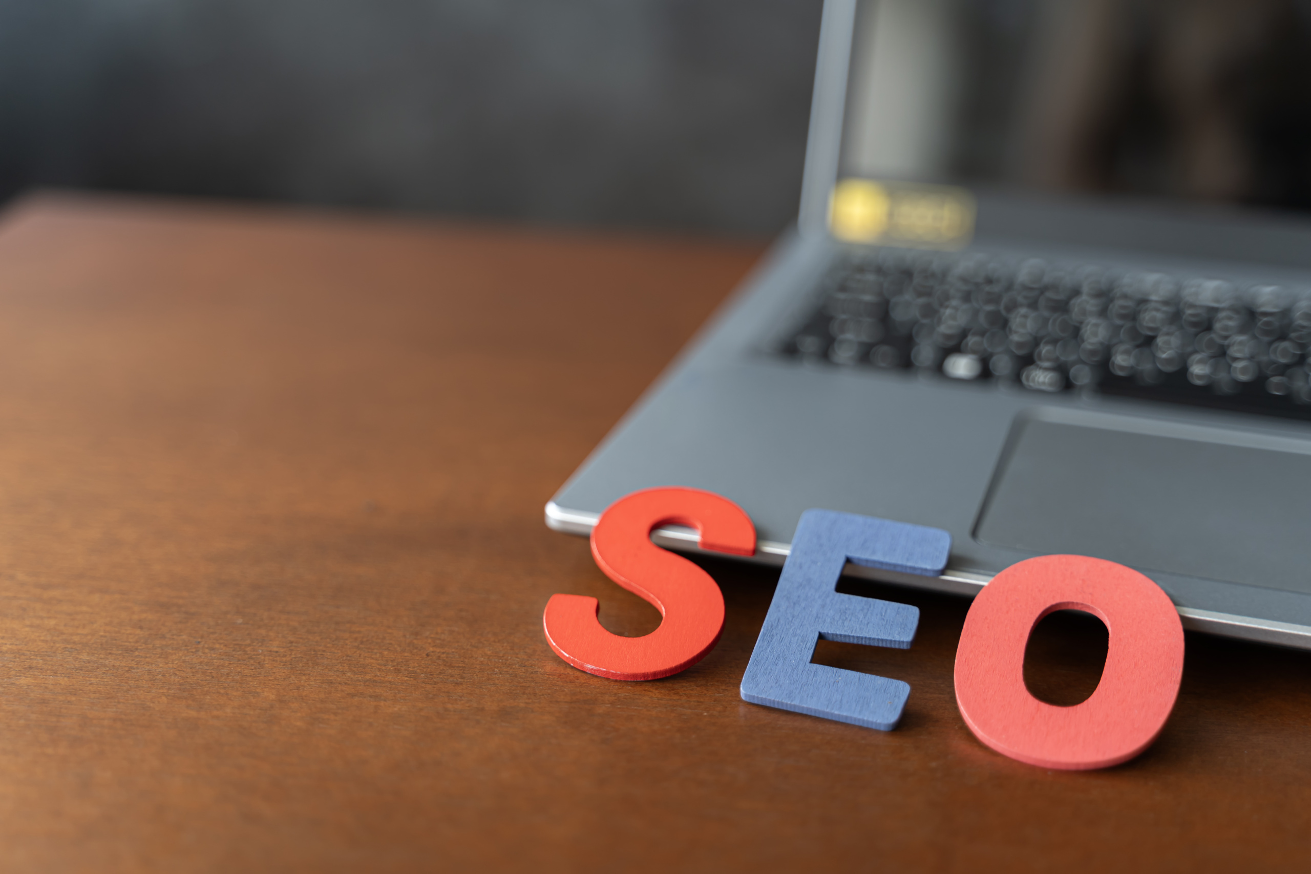 Wooden letter stands for SEO abbreviation lying on laptop at des