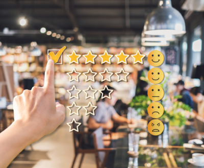 Young woman traveler using smartphone to give a five-star satisfaction rating of the food and drinks at restaurant on social media, Travel lifestyle concept